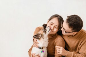 Happy couple with their dog in a joyful studio portrait on white background.