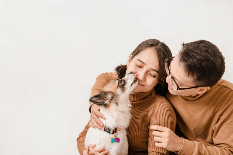 Happy couple with their dog in a joyful studio portrait on white background.